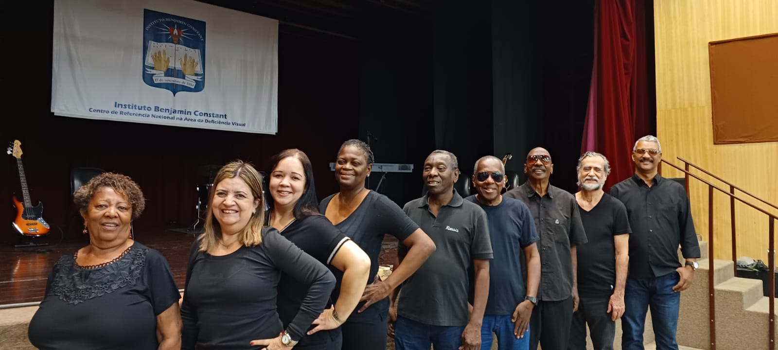 Grupo Ponto de Vista com 4 mulheres e 5 homens em fila, todos com roupa preta